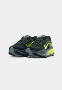 Nike bėgimo bateliai tamsiai žaliu atspalviu su ryškiais geltonais akcentais. Akių viršus su tekstūruotu paviršiumi, paminkštintas padas ir raštuotas protektorius.