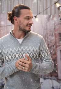 Szary sweter z dzianiny z kołnierzem na zamek półmetrowym, zdobiony białymi i brązowymi wzorami w romby na klatce piersiowej oraz ściągaczami na rękawach. Casualowy styl zimowy.