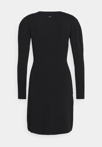 Robe en maille noire à manches longues, texture côtelée, coupe ajustée, col rond et fente sur le côté à l'ourlet. Aucun matériel ni motif visible.