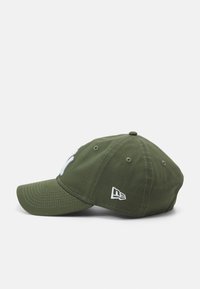 Green baseball cap with a curved visor, embroidered logo in white, six ventilation eyelets, and a small brand logo on the side.