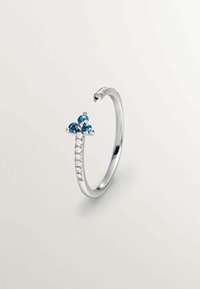 Anillo de plata con tres gemas azules dispuestas en un diseño floral, y una banda acentuada por pequeñas piedras claras a lo largo de un lado.