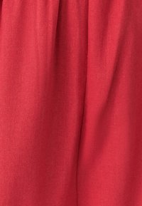 Rødt stof med en blød tekstur og en let glans. Materialet er let og falder smukt, med subtile farvevariationer.