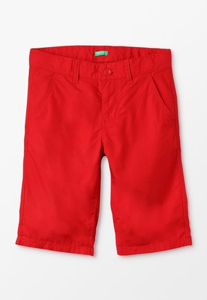 Rote kniehohe Shorts mit vorderer Knopfleiste, Reißverschluss, Gürtelschlaufen und zwei Vordertaschen vor weißem Hintergrund.
