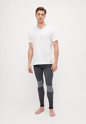 Balta V formos iškirptė t-shirt, derinama su prigludusiomis juodomis leggingais, turinčiomis tekstūrinius intarpus ir atspindinčius akcentus.