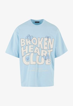 Light blue cotton t-shirt with short sleeves, featuring a large "BROKEN HEART CLUB" print in bold white letters and blue heart icons.