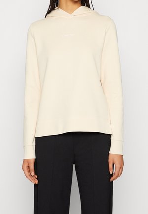 Hoodie beige clair à manches longues, avec capuche ajustable à cordon, et un logo Calvin Klein discret sur la poitrine. Tissu doux et coupe décontractée.