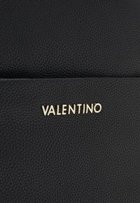 Black leather material with a textured finish, featuring a gold "VALENTINO" logo. Simple, elegant design with a structured shape.