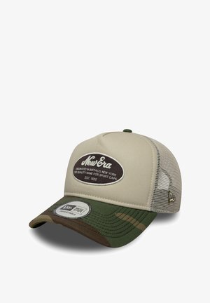 Beżowa czapka z zielonym daszkiem w kamuflażu. Posiada naszywkę New Era z przodu, siateczkowe boki oraz regulowane zapięcie snapback.