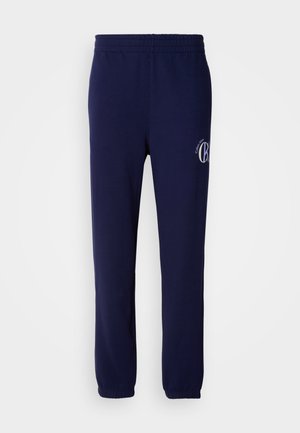 Pantaloni de trening bleumarin dintr-un amestec de bumbac. Au talie elastică, picioare tapered și un logo mic pe partea stângă.