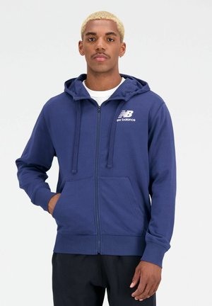 Felpa con zip blu navy, con coulisse, tasche frontali, polsini a costine e logo New Balance bianco sul lato sinistro del petto. Tessuto morbido in misto cotone.