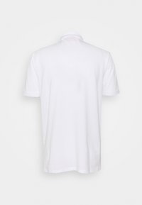 Polo shirt blanc uni à manches courtes vu de dos avec un col classique sur un fond neutre.