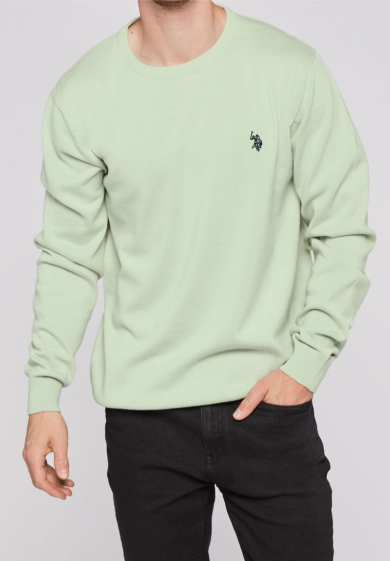 Lichtgroene crewneck trui gemaakt van zachte stof, met ribgebreide manchetten en een klein zwart logo op de linker borst. Draag het met een donkere jeans.