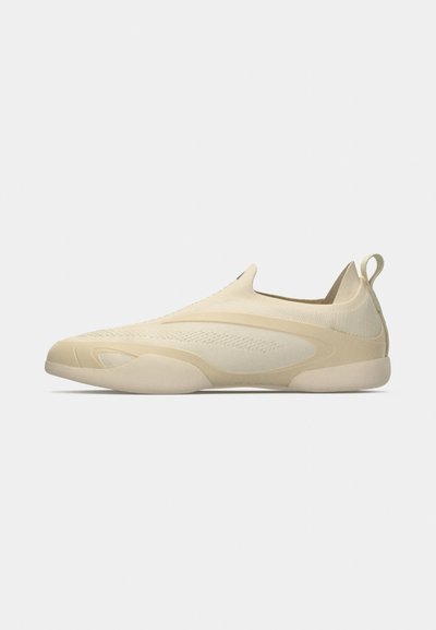 Lichtbeige instapsneaker met gebreid bovenwerk, naadloos ontwerp, een trekband aan de hiel en een gladde rubberen zool, zijaanzicht op een witte achtergrond.