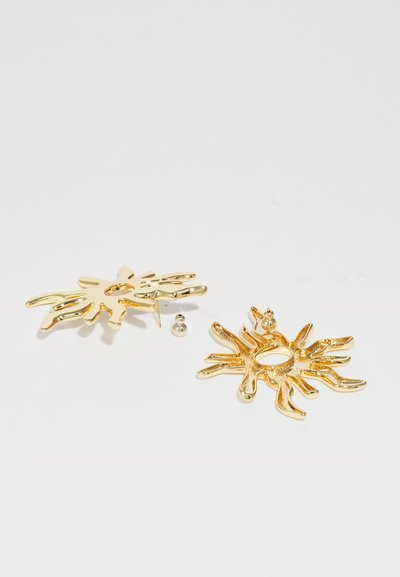 Gold-tone metal earrings featuring a sunburst design with textured accents and open centers, accompanied by matching hardware.