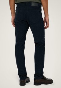 Marineblauwe broek van soft stof, met een slim fit, achterzakken met een lichte hoek, en een taillabel detail.