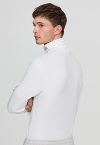 Biała, długosleeve, golfowa bluzka wykonana z gładkiego, elastycznego materiału. Fason jest dopasowany, z wysokim kołnierzem i minimalistycznym designem.