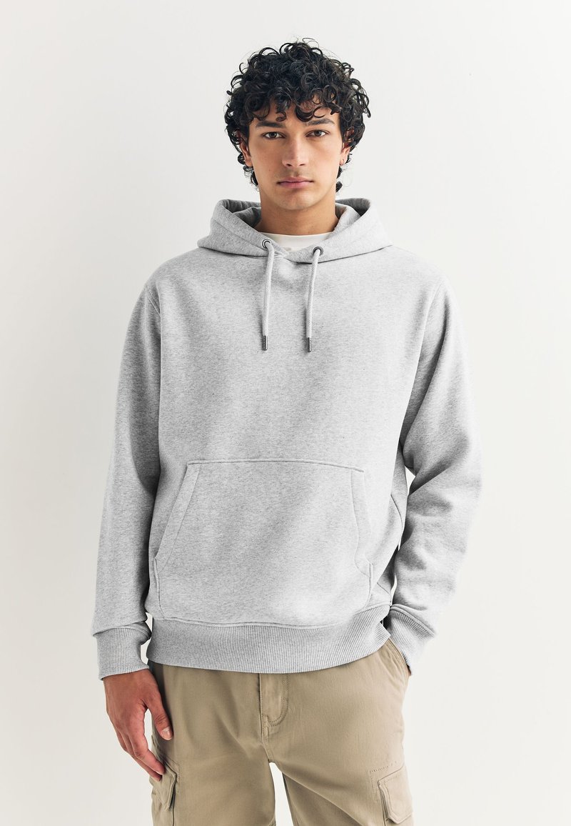 Sweat-shirt gris à capuche en tissu doux, avec une poche avant et des poignets côtelés. Assorti à un pantalon cargo beige clair.