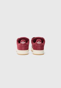 Bordo suede tenisice s bijelim logotipom na peti i kremasto bijelom đonu. Imaju nisku siluetu i zaobljeni vrh.