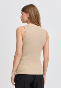 Beež ühtlane tank top ribatud tekstuuriga, ilma varrukateta ja ümmarguse kaelusega; lihtne ja mitmekülgne siluett.