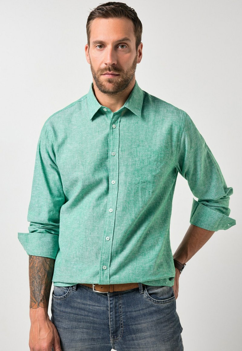 Camisa de botones verde claro hecha de tela texturizada, con un bolsillo en el lado izquierdo, mangas remangadas y botones blancos.