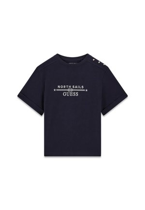 Camiseta azul marino de manga corta con puños doblados, logo blanco "North Sails Guess" centrado y tres botones dorados en el hombro izquierdo.