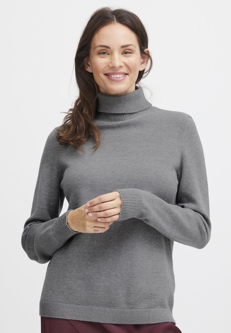 Hallide grey turtleneck-sweater, mis on valmistatud pehmest kudumist, millel on pikad varrukad ja soonikkoes mansetid. Mudel hoiab käsi vöökohal.