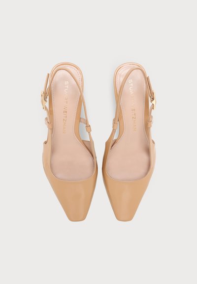 Paire d'escarpins slingback beige à bout pointu avec brides à la cheville et boucles dorées, vus de dessus sur un fond clair.