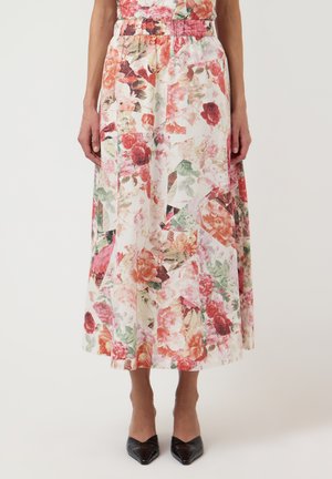 Mellemlang blomster nederdel i pink, rød og grønne toner med elastisk talje, båret med sorte spidse hæle.