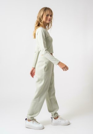 Lys grønn avkortet langermet topp sammen med matchende joggebukser. Begge plaggene har myk fabrik og en avslappet passform, supplert med hvite sneakers.