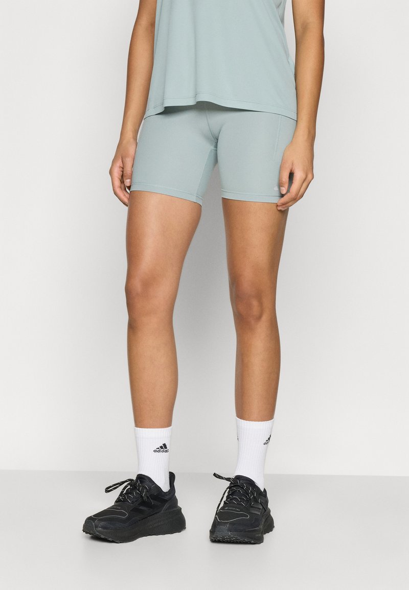 Light blue athletic shorts made of stretchy fabric, paired with black sneakers and white crew socks. The top is a loose-fitting grey shirt.