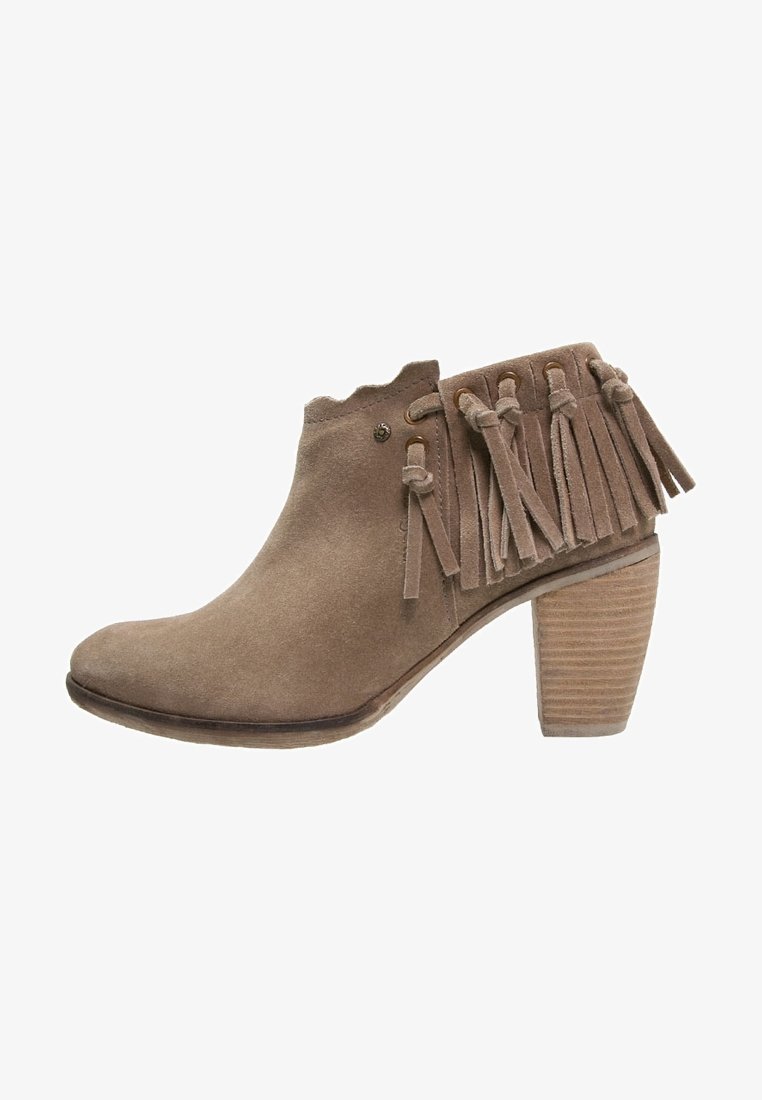 Bottine en daim taupe montant à la cheville avec un talon carré empilé et des franges sur le côté et à l'arrière.