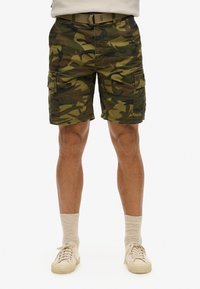 Pantalones cortos cargo de camuflaje en verde y marrón, con bolsillos laterales, un cinturón y un corte relajado. Fabricados con un tejido duradero y una superficie texturada.