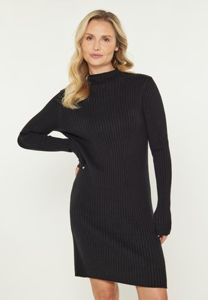 Schwarzes Rippstrickkleid mit langen Ärmeln und hohem Ausschnitt. Gerader Schnitt, bis zur Mitte des Oberschenkels, weiche Textur, nahtloses Design.