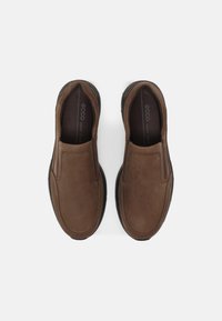 Barna bőr slip-on cipők lekerekített orral, elasztikus oldalpanellel és mintázott gumi talppal. Belső része puha szövetbéléssel rendelkezik.
