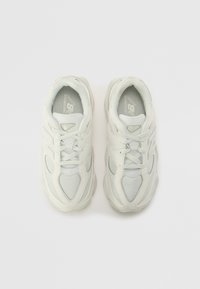 Baskets de sport blanches avec un dessus en mesh et synthétique, présentant un orteil arrondi, un laçage et un logo bien en vue sur la languette.