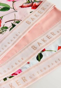 Drei pastellrosa Unterwäschebunds mit Blumenmuster und roségoldenen "TED BAKER"-Logos auf weißem Hintergrund.