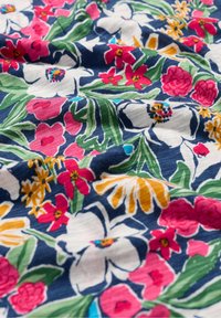 Gėlių audinys su ryškiai rožinėmis, raudonomis ir geltonomis gėlėmis ant tamsiai mėlyno fono. Lygus paviršius su išsamiais botaniniais raštais.