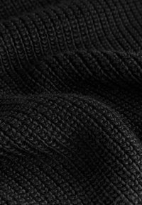 Black knitted fabric with a textured, ribbed pattern. The material appears soft and dense, showcasing a subtle sheen in certain areas.