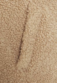Béžová texturovaná tkanina s měkkým, chlupatým povrchem. Materiál má kudrnatý vlas a hladký, mírně vystouplý pruh.