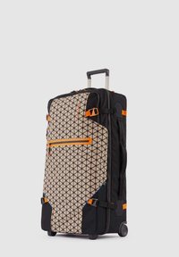 Lange zwarte en beige koffer op wielen met geometrisch patroon, oranje ritssluiting, riemen en een uitgeschoven telescopische handgreep.