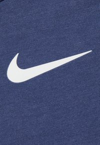 Tecido azul marinho com uma superfície texturizada apresentando um proeminente logo da Nike em branco.