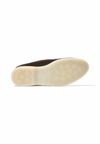 Zapato de ante marrón sin cordones con una suela de goma blanca texturizada que presenta patrones de agarre circulares y un diseño de puntera suave y redondeada.