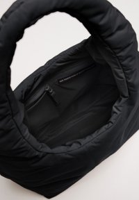 Borsa a tracolla nera imbottita realizzata con reti da pesca riciclate. Presenta un manico arrotondato e una tasca interna con zip per uno stoccaggio sicuro.