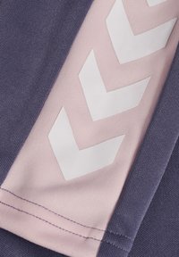 Dunkellila Stoff mit strukturierter Oberfläche, mit einem hellrosa Abschnitt, der weiße Chevron-Muster aufweist. Nahtdetails sichtbar.