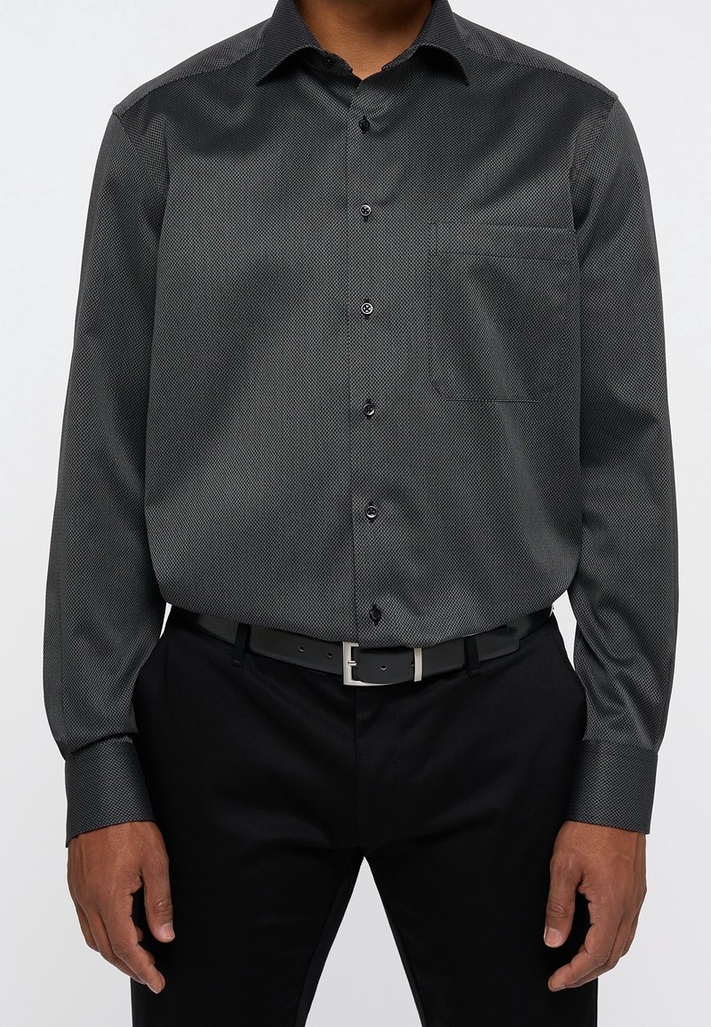 Zwart patroon overhemd met lange mouwen, voorzien van knoopsluiting aan de voorkant, scherpe kraag, borstzak en manchetten, gedragen met een zwarte broek en een riem.