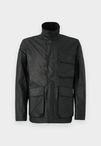 Black jacket made of textured fabric, featuring a high collar, snap buttons, and four front pockets. Includes logo patch on the sleeve.