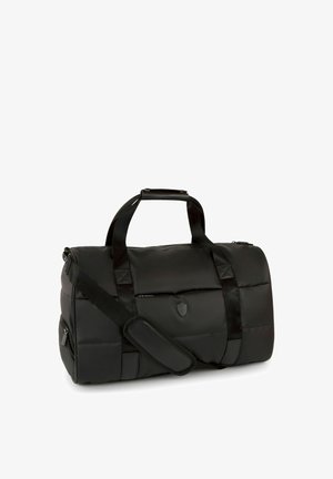 Sac polochon noir matelassé avec doubles poignées, bandoulière réglable avec coussinet, poches zippées et logo en forme de bouclier sur le devant.