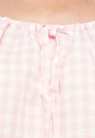 Tissu vichy rose avec une texture froissée, doté d'un col élastique et d'une petite fermeture nouée à l'avant.