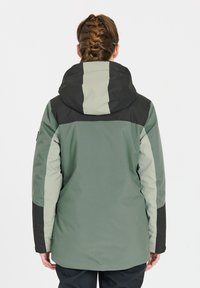 Geïsoleerde jas in groene tinten met een zwarte capuchon, met een kleurblokken ontwerp en een gladde, duurzame textuur. Verstelbare capuchon en mouwen.