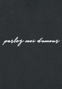 Tissu noir avec du texte en cursive blanche en relief "parlez moi d'amour" au centre. La texture semble lisse avec un léger motif côtelé.